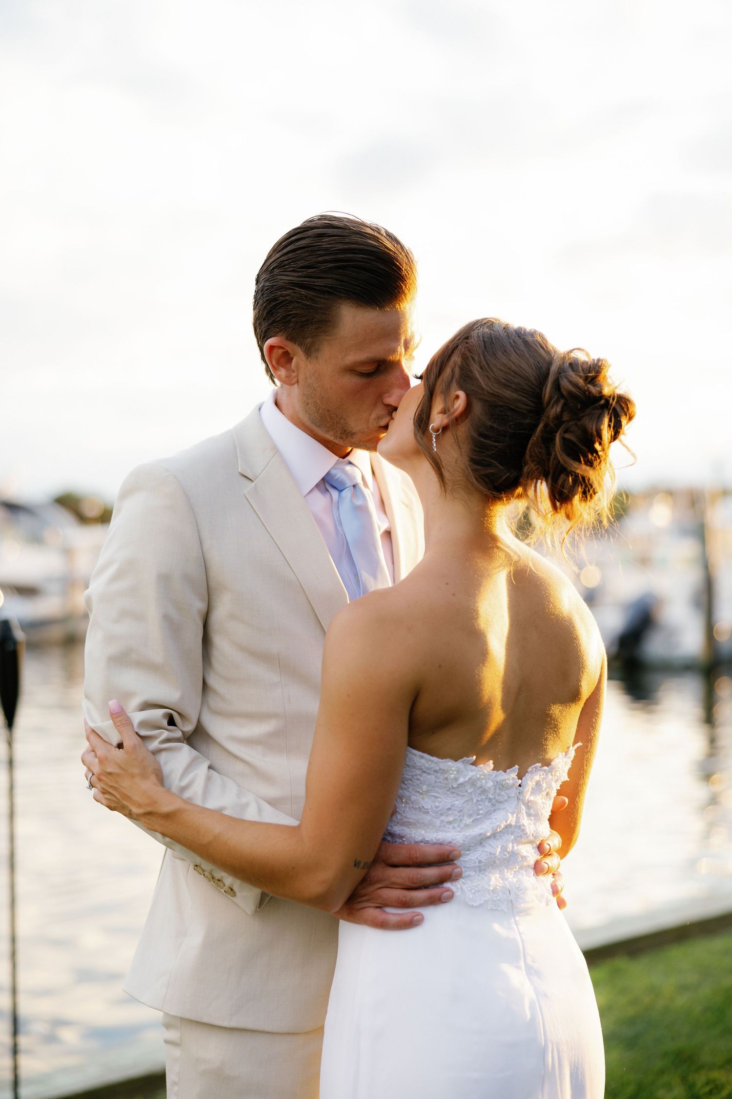A romantic sunset wedding photo series showing a couple embracing by the waterfront.