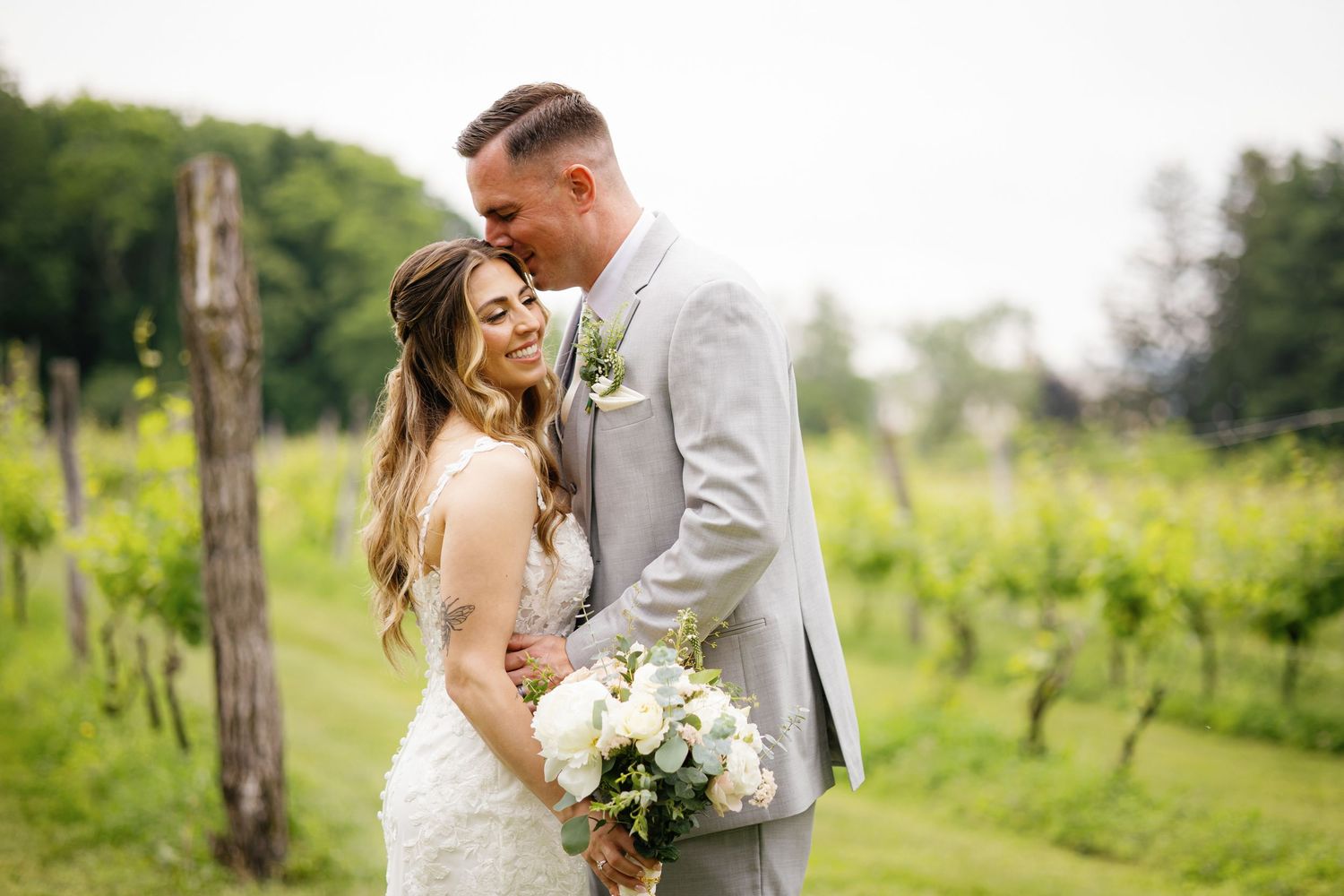 Couple embraces in a romantic outdoor setting surrounded by lush greenery and natural light.