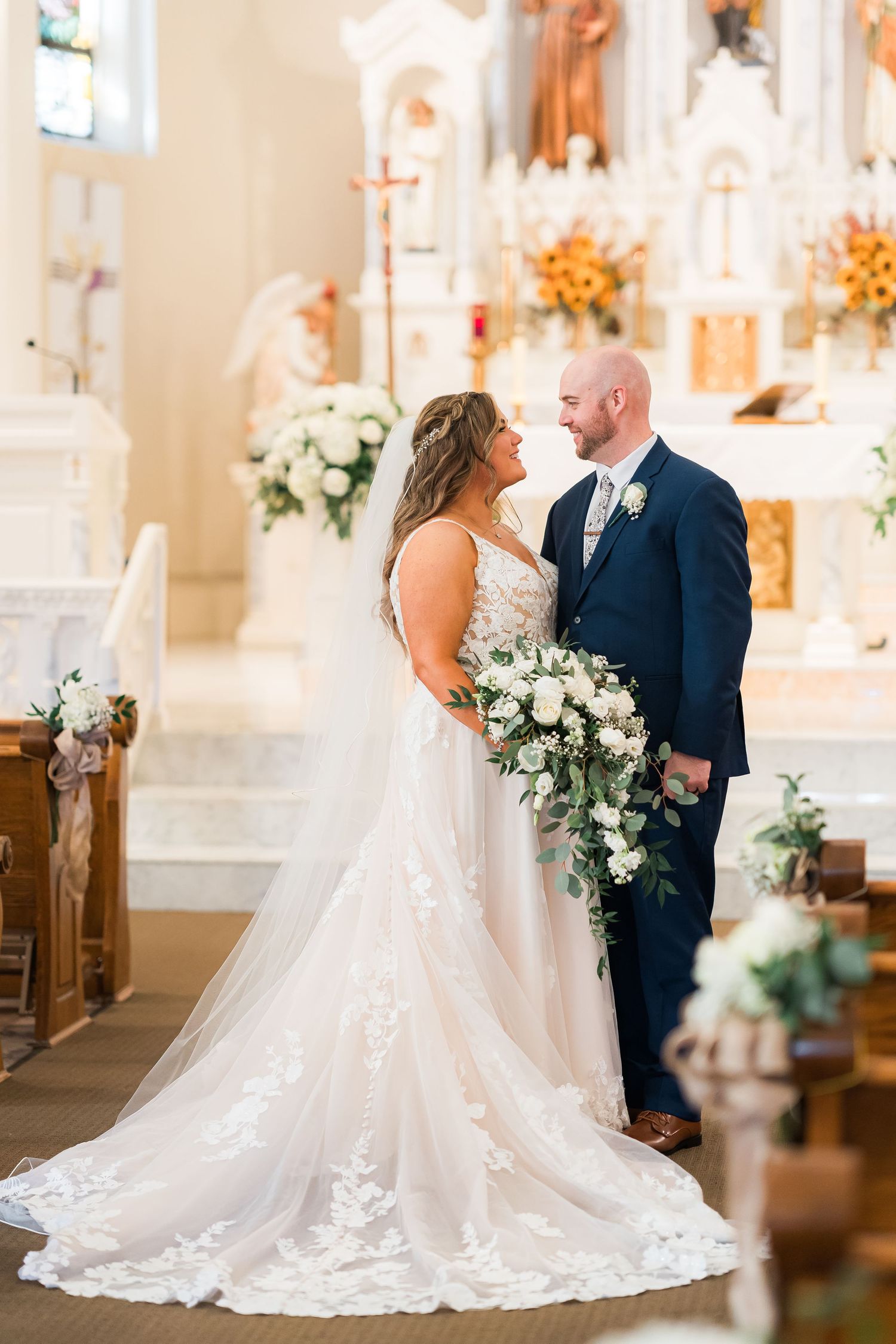 An intimate wedding ceremony moment in a beautiful church decorated with white flowers and golden accents.