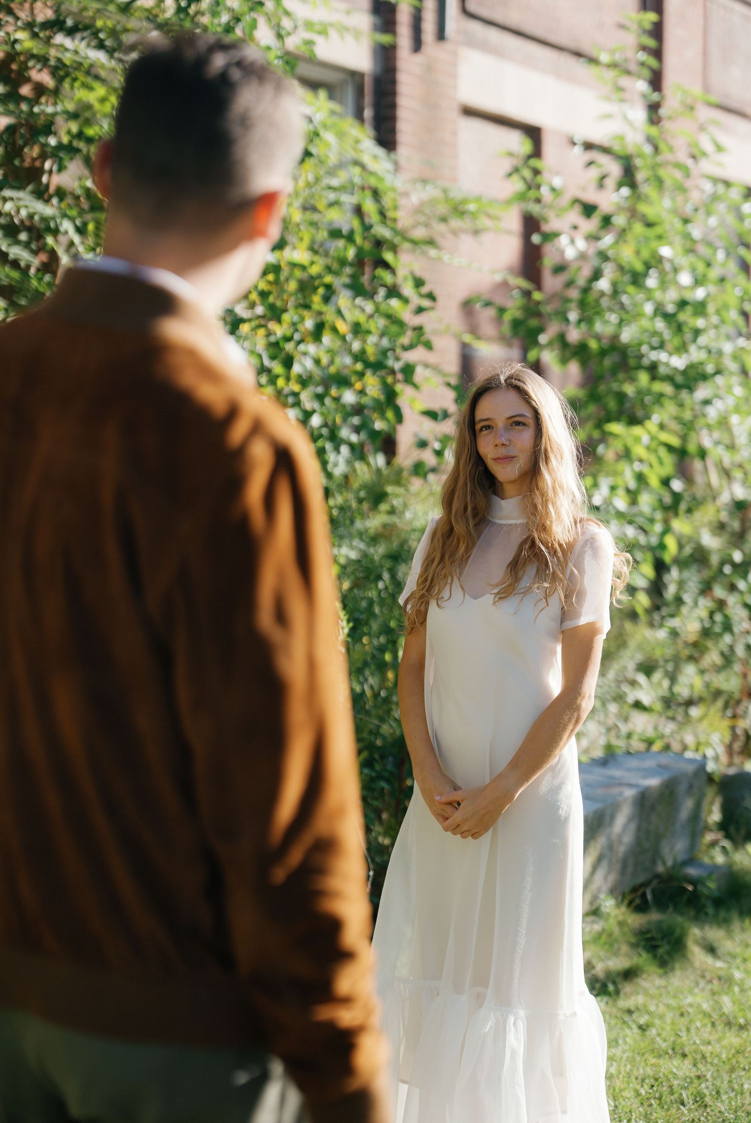 A series of outdoor photos showing someone in a white dress and another person in a brown jacket in a garden setting.
