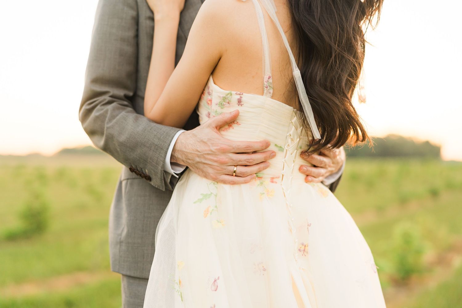 A romantic wedding moment captured in soft light with a flowing white dress and grey suit.