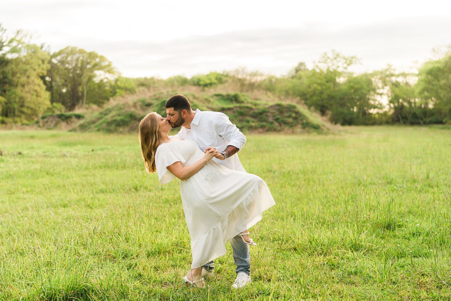 A tender embrace captured during a summer countryside photoshoot in a green meadow.