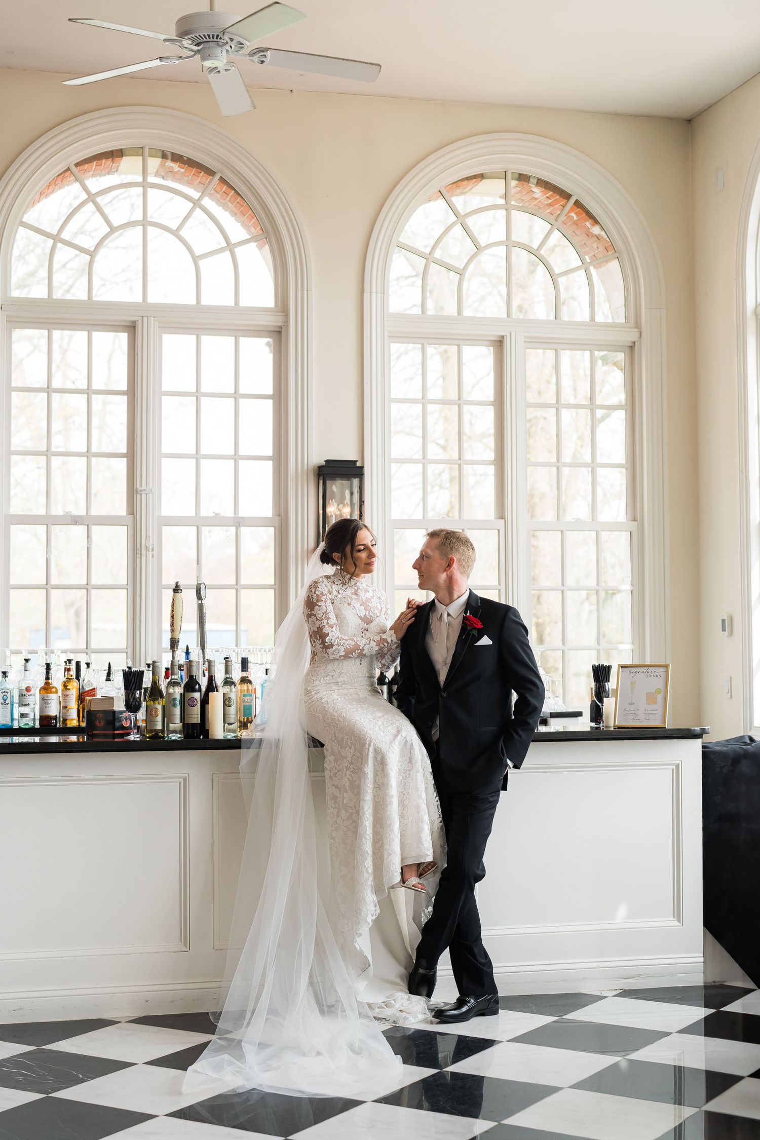 Bride sits on custom bar next to groom at indoor Long Island wedding venue