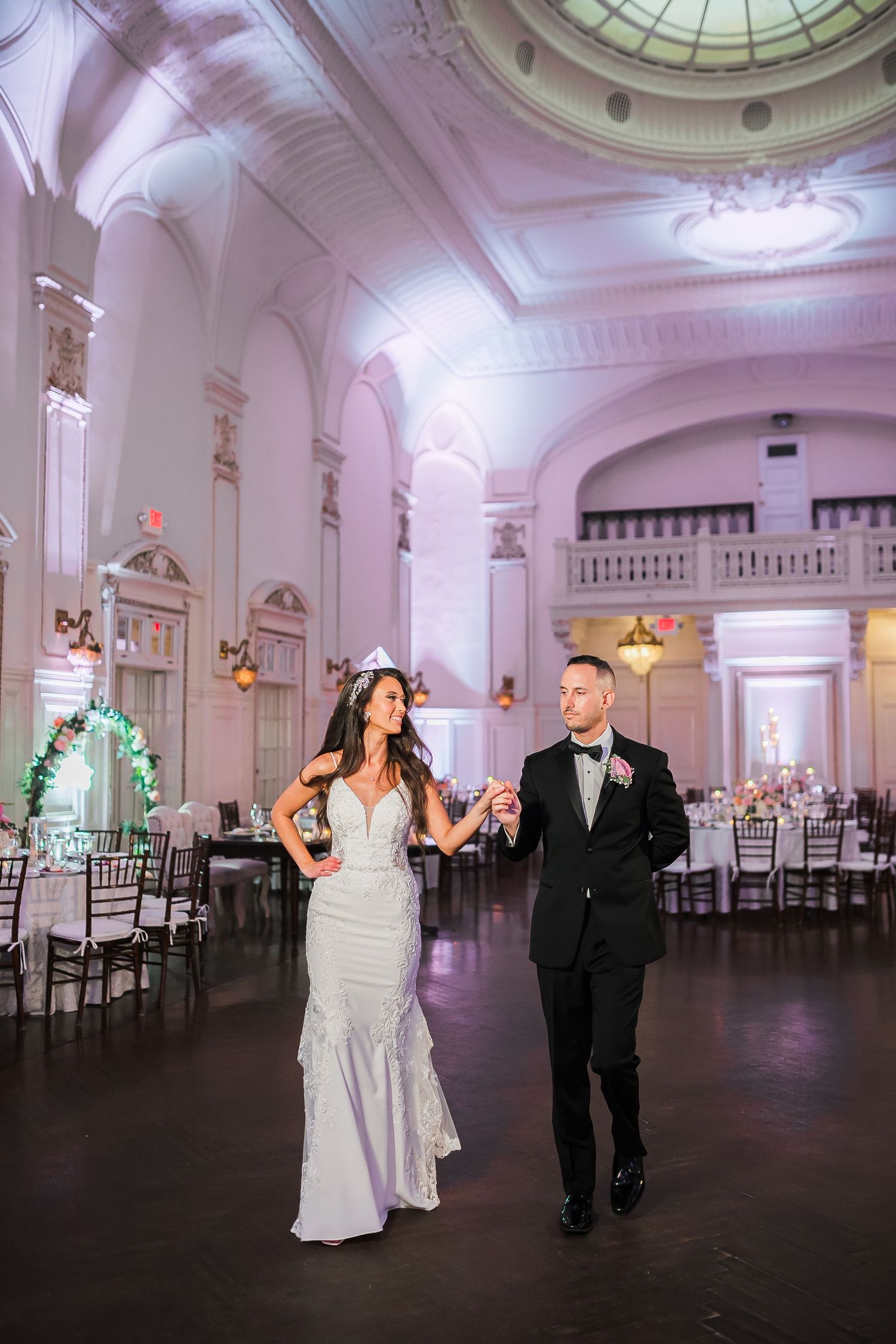 A romantic wedding celebration in an elegant ballroom venue with ornate architectural details and decorative lighting.