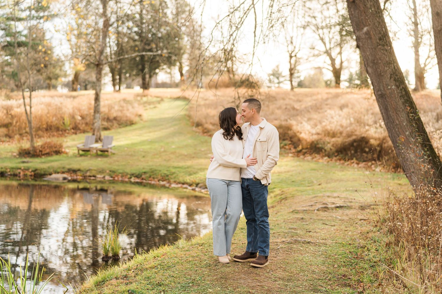 Couple shares an intimate moment while walking along a peaceful pond path during autumn.