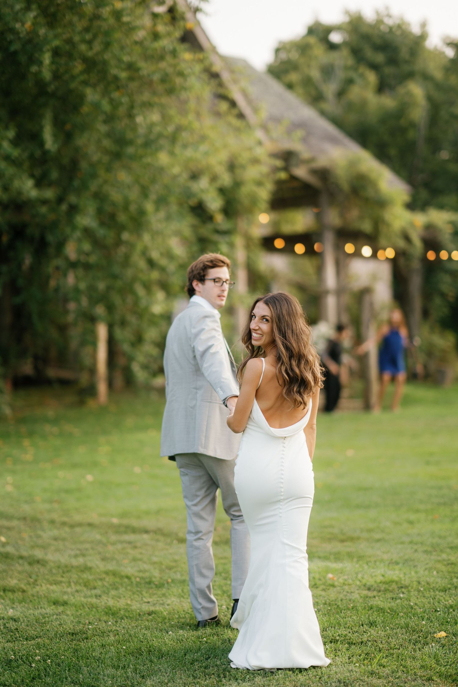 A couple shares an intimate moment on a grassy lawn at an outdoor wedding venue during golden hour.