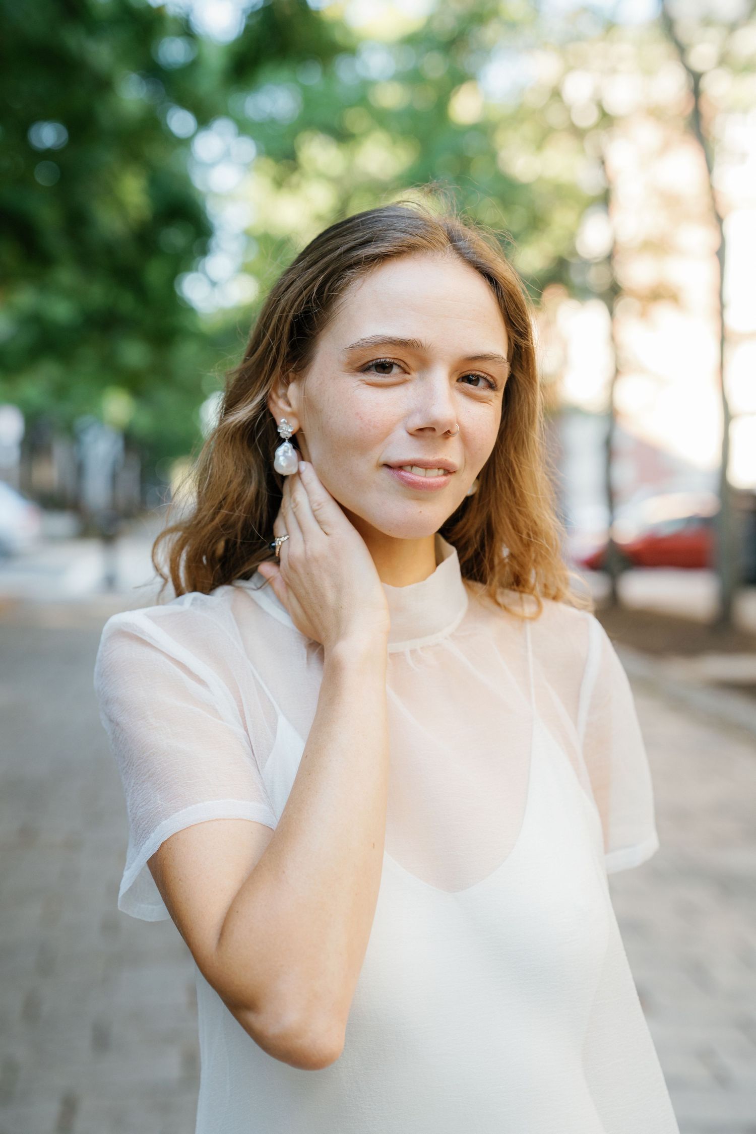 A series of outdoor portrait photographs showing someone in a white top against a soft green natural background.