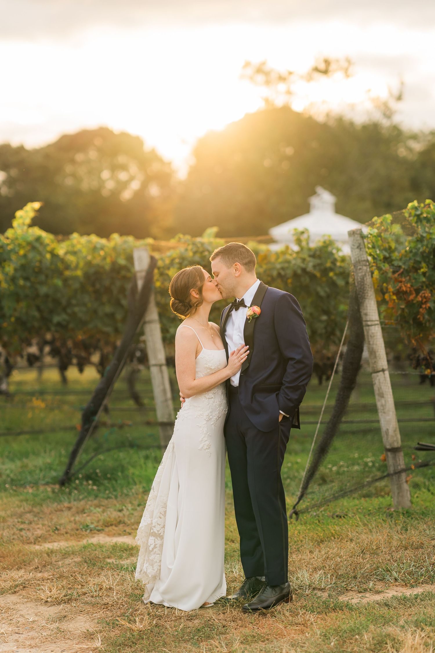 Romantic sunset wedding photo of newlyweds sharing an intimate moment in a vineyard.