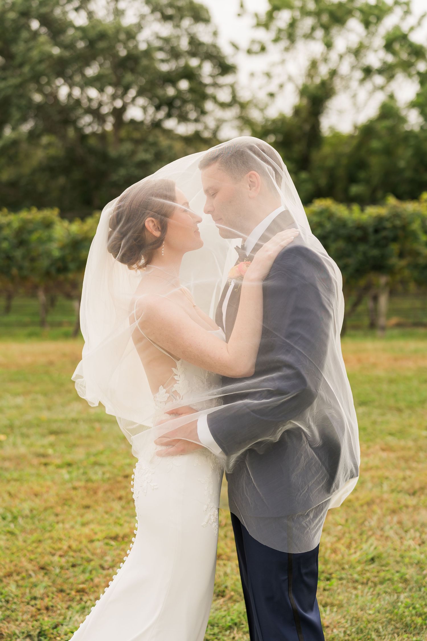 Bride and groom pose under veil for Suffolk County wedding photograph