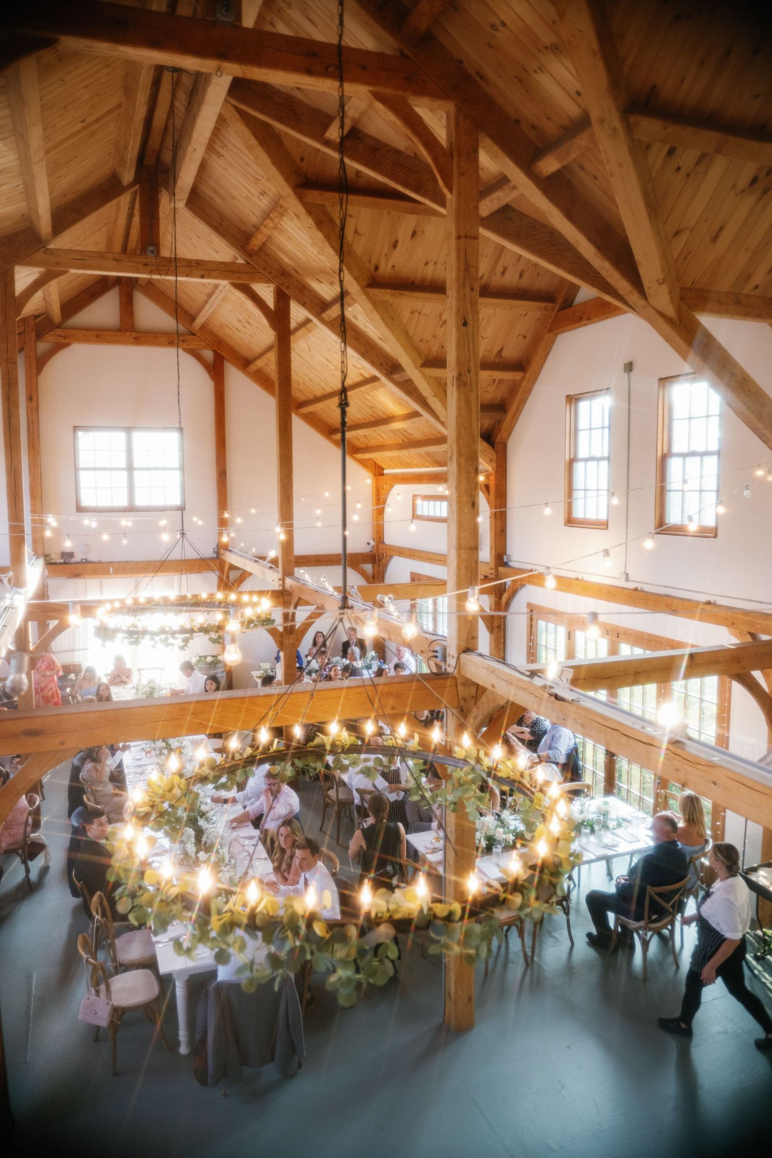 A rustic timber-framed wedding reception venue with string lights and floral decorations creating a warm, inviting atmosphere.