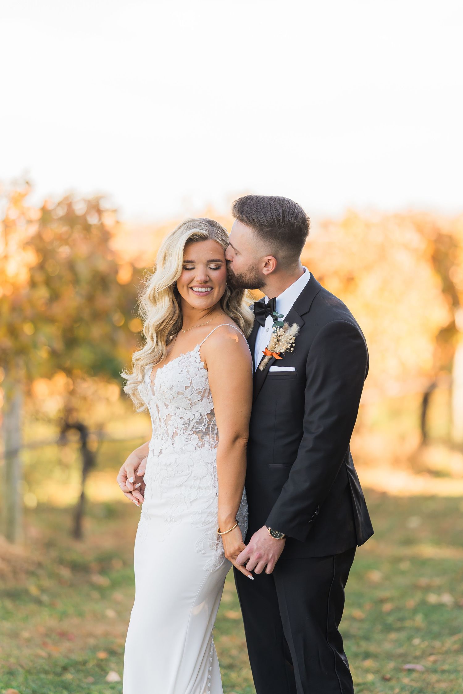 Newlywed couple sharing an intimate sunset moment outdoors with warm golden lighting and fall foliage.
