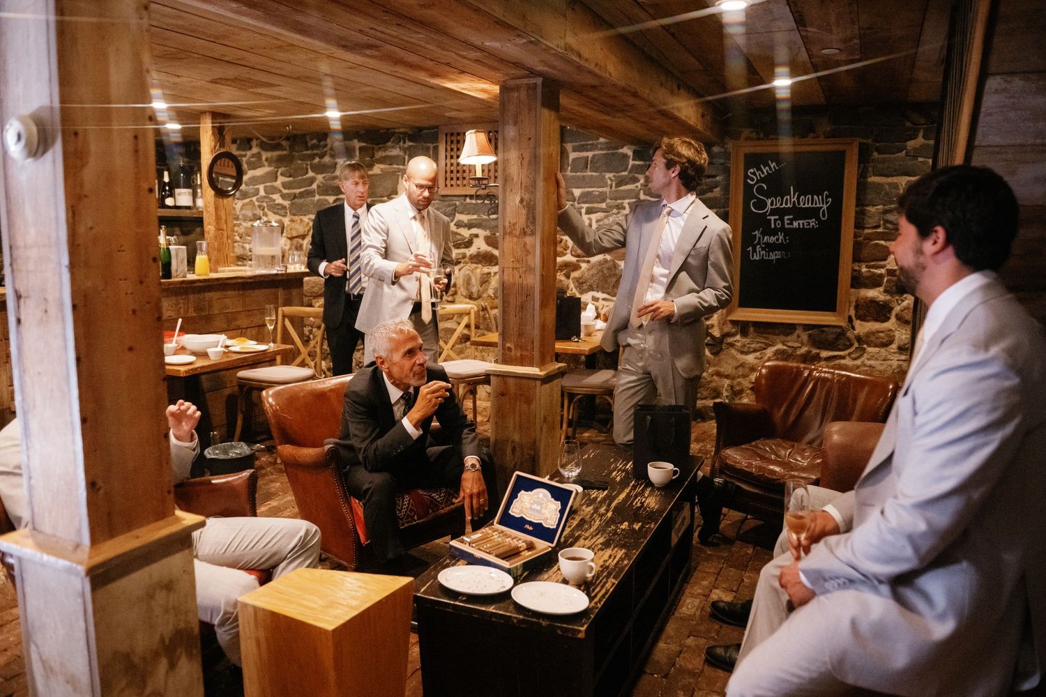 Chefs working in a rustic restaurant kitchen with wooden beams and warm lighting prepare dishes at various stations.