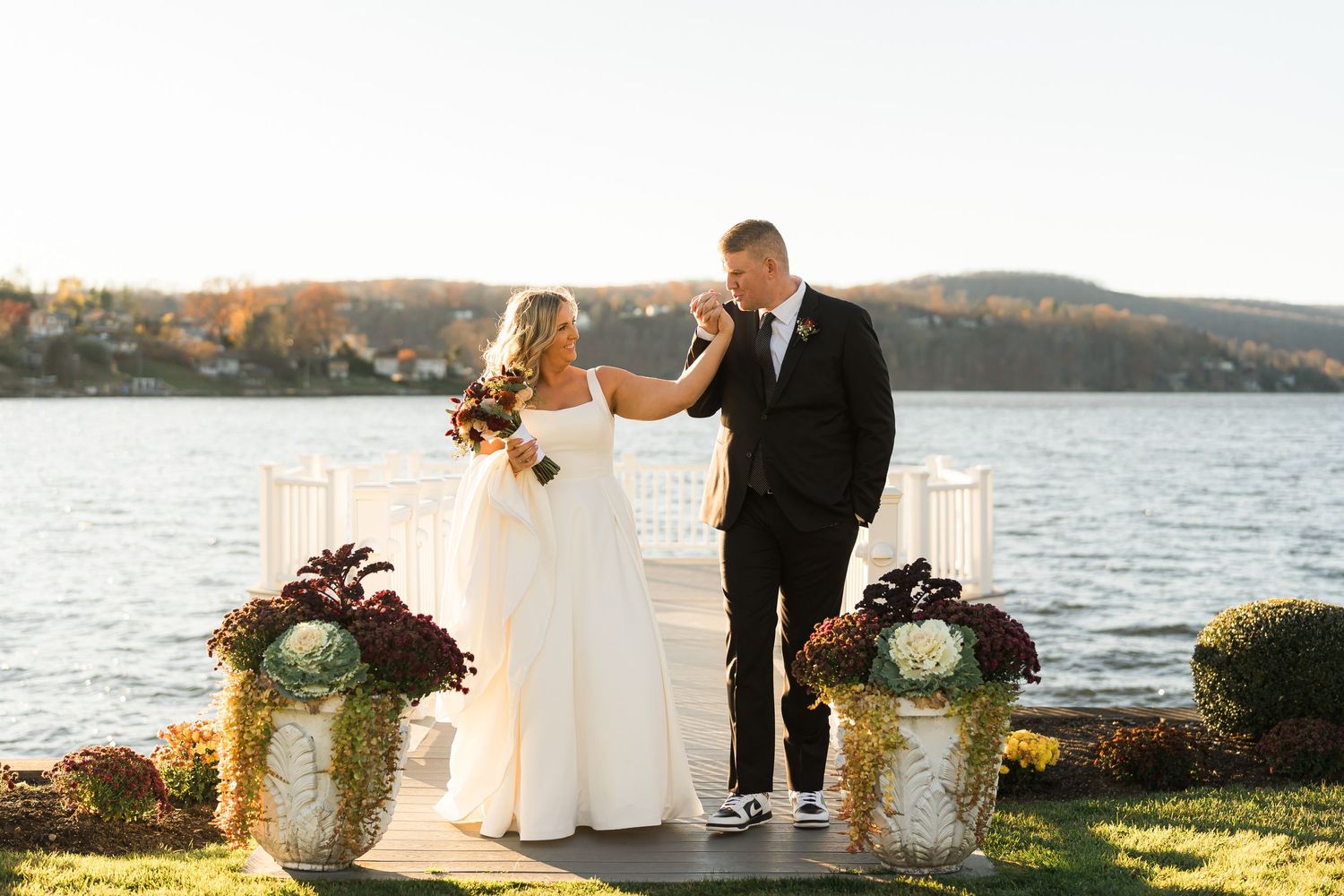 Wedding ceremony setup by the lake with floral arrangements at sunset.