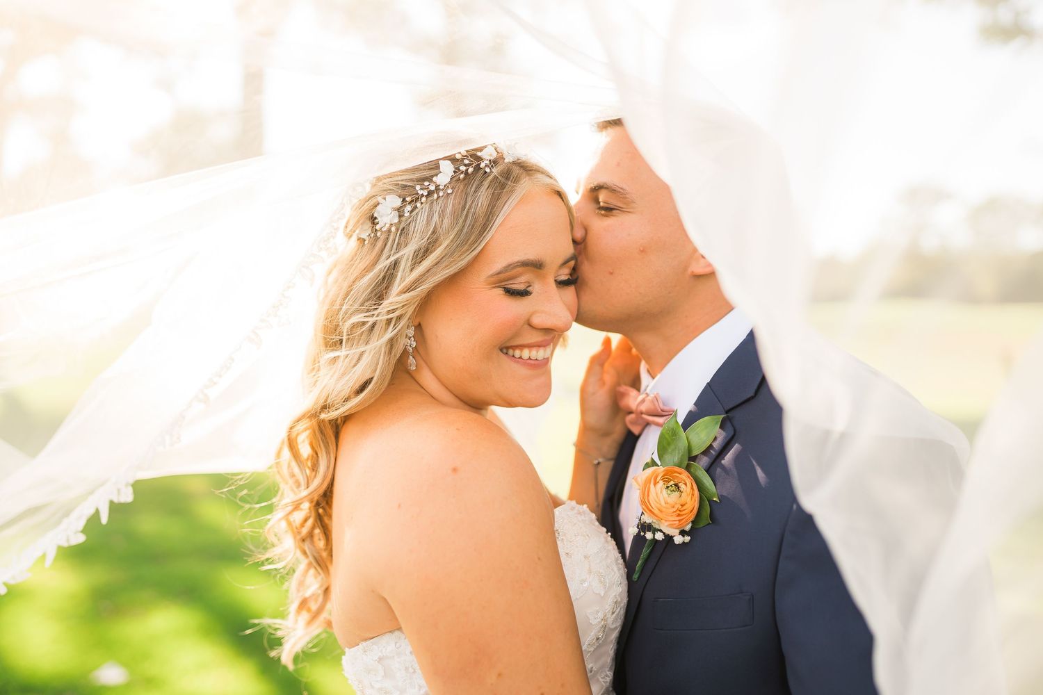 Groom kisses bride under veil in outdoor wedding on Long Island