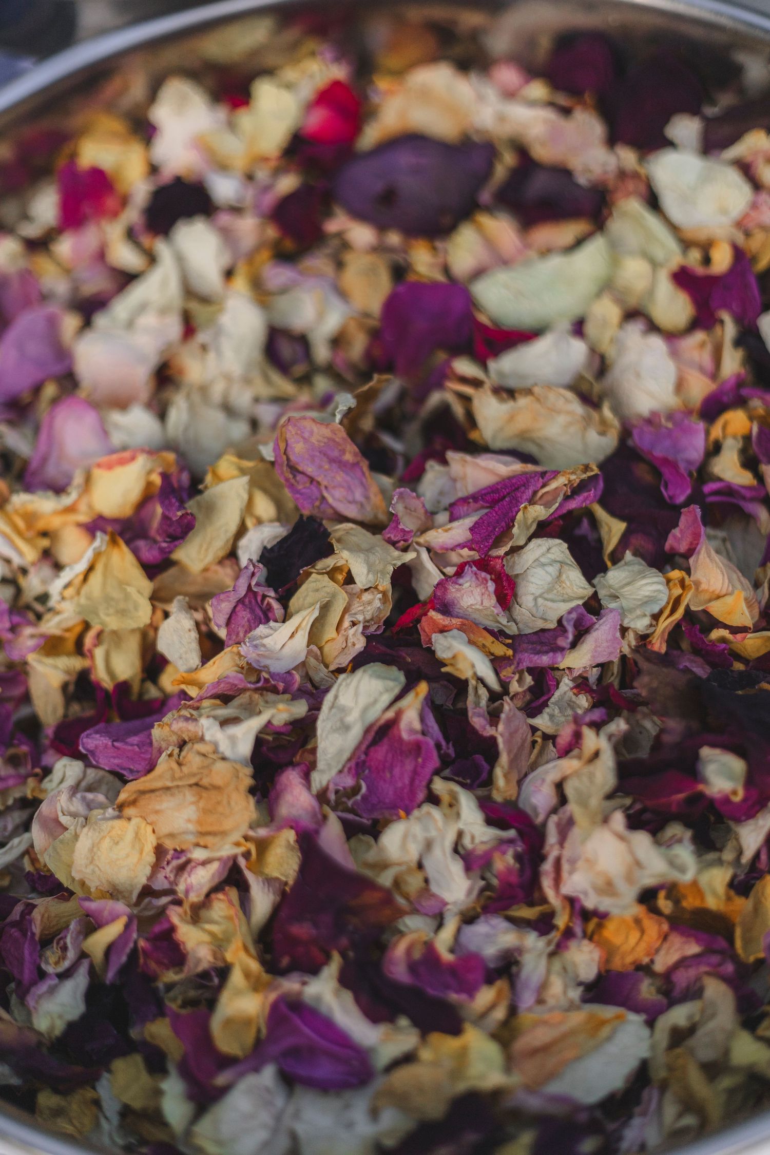 Colorful mixture of dried flower petals in a metal bowl.