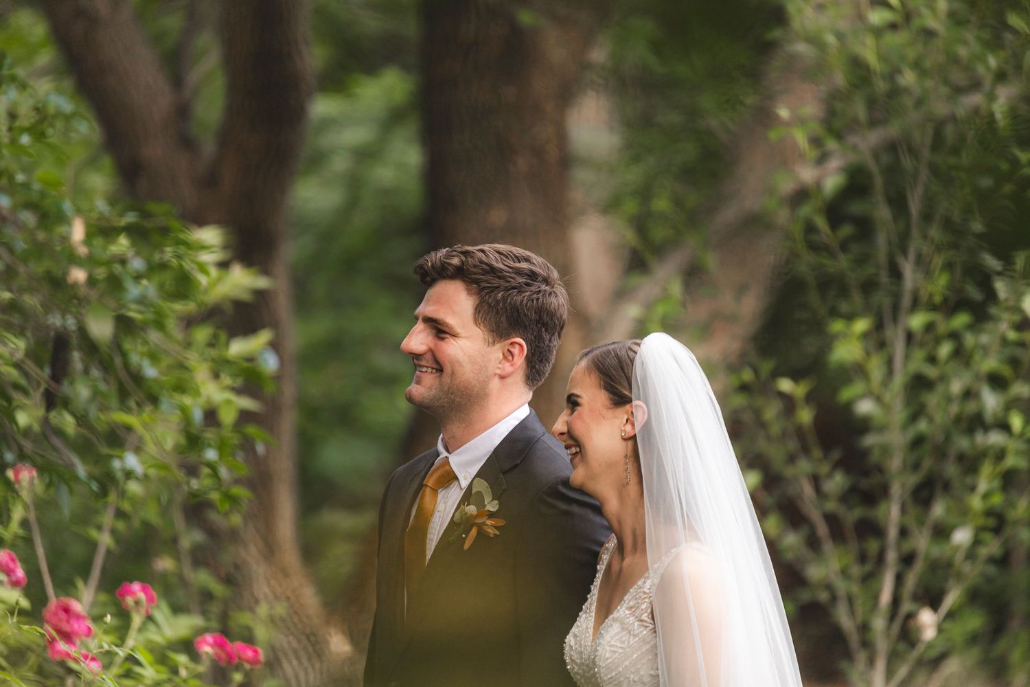 A wedding couple shares a joyful moment together in a lush garden setting.