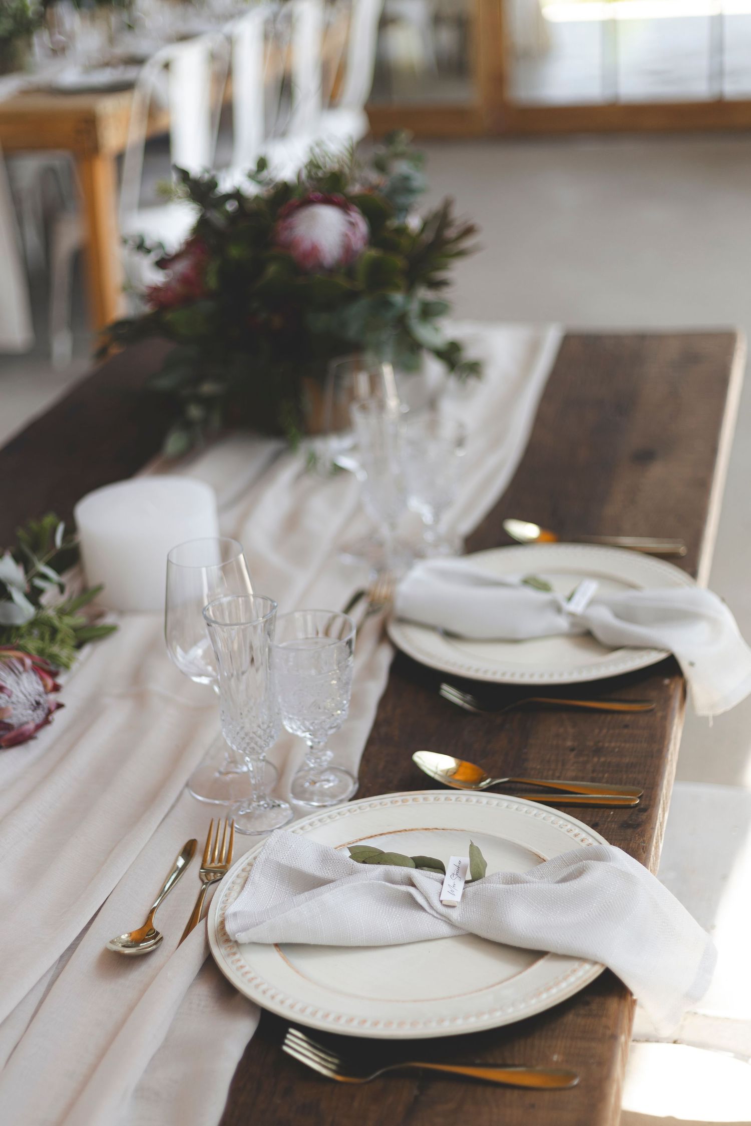 Close-up of wedding table setting with white linens and floral accents.