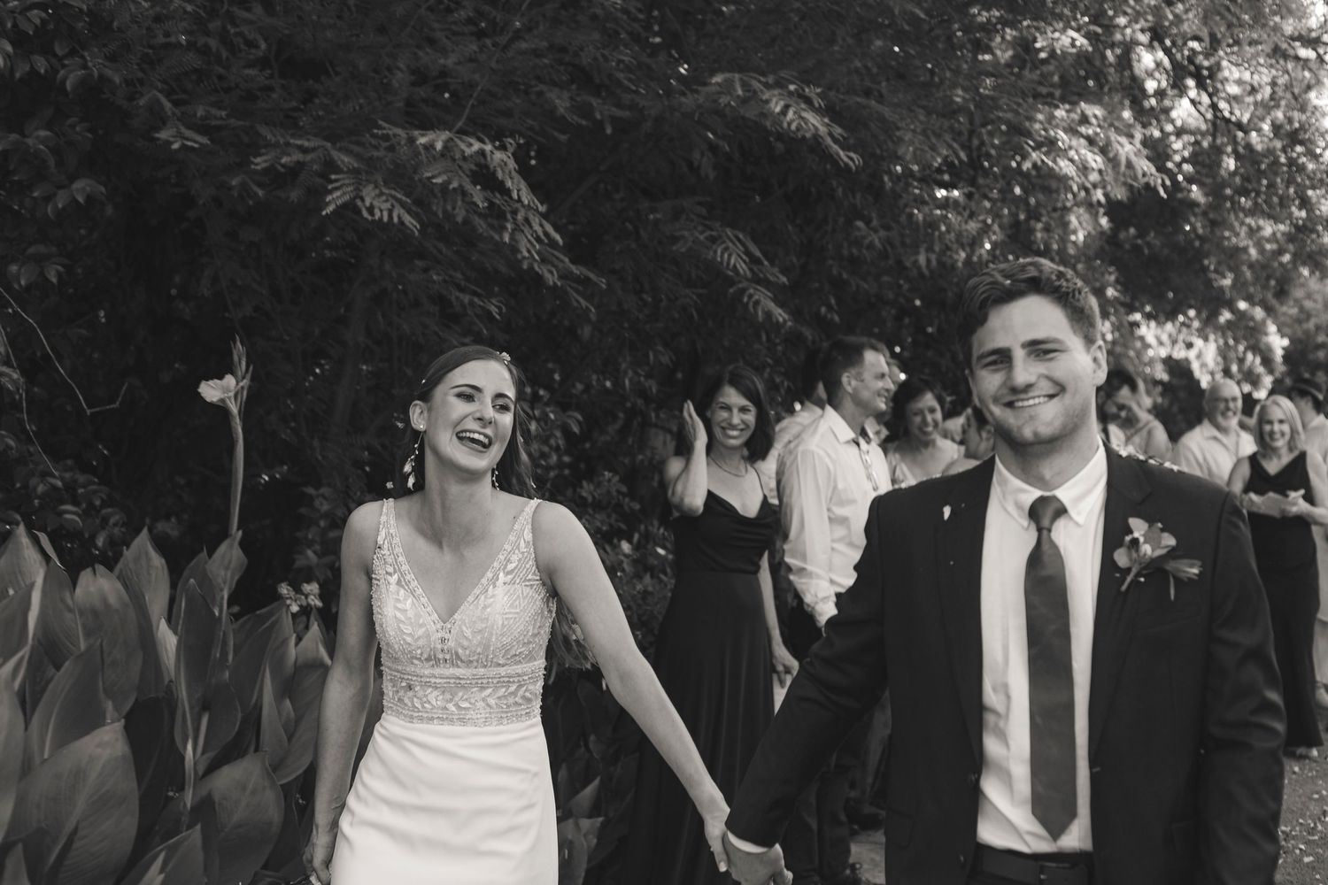 Black and white photo of newlyweds walking together outdoors after their wedding ceremony.