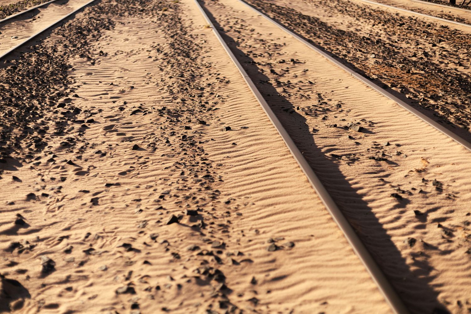 Railroad tracks in sandy desert terrain creating strong diagonal lines and patterns.