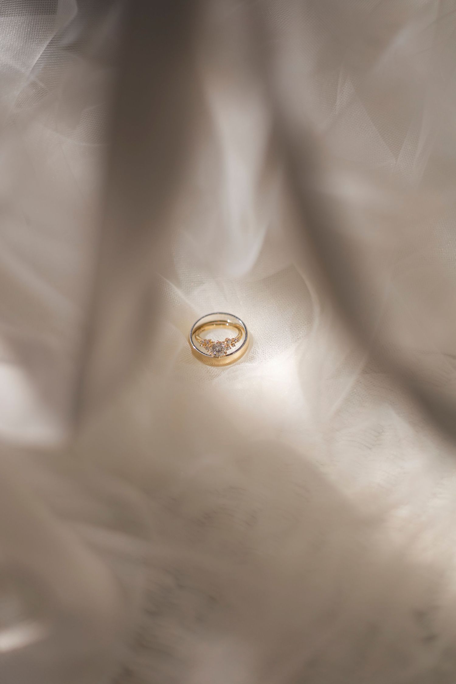 Gold wedding ring photographed with dreamy soft focus effect on light fabric.