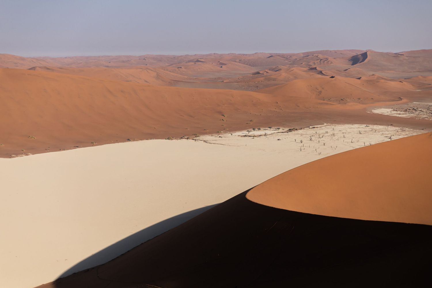 Dramatic red sand dunes and white clay pan in the Namib Desert.