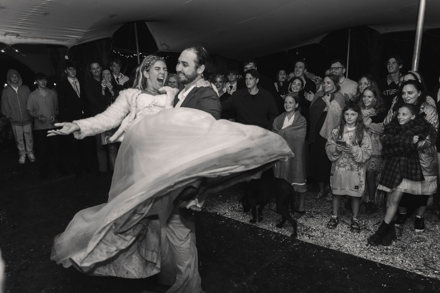 Black and white photo of a groom spinning his bride on the dance floor at their wedding reception.