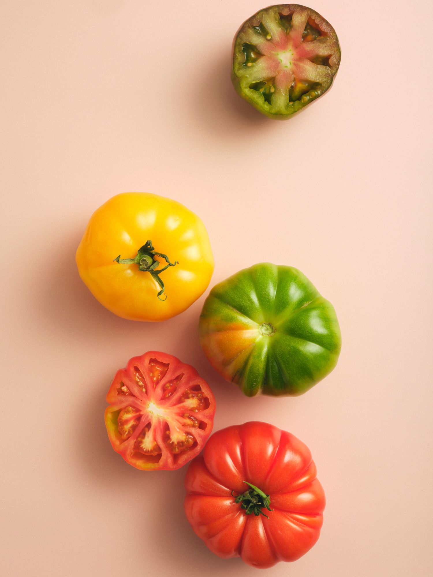 Graphic style shot of heirloom tomatoes on a peach background