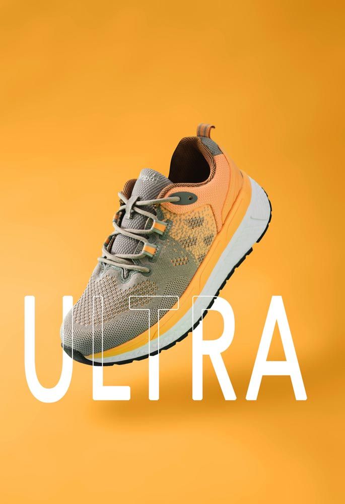Propet sneaker suspended with a shadow on an orange background