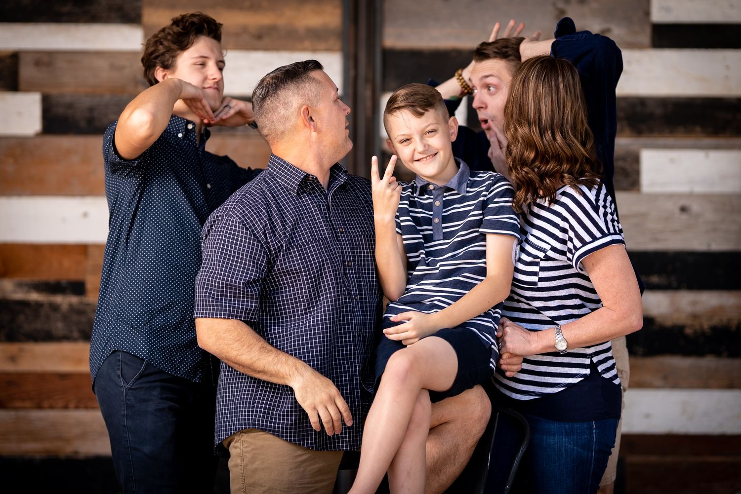 A family shares laughter and joy together while sitting on wooden steps during a casual outdoor photo session.
