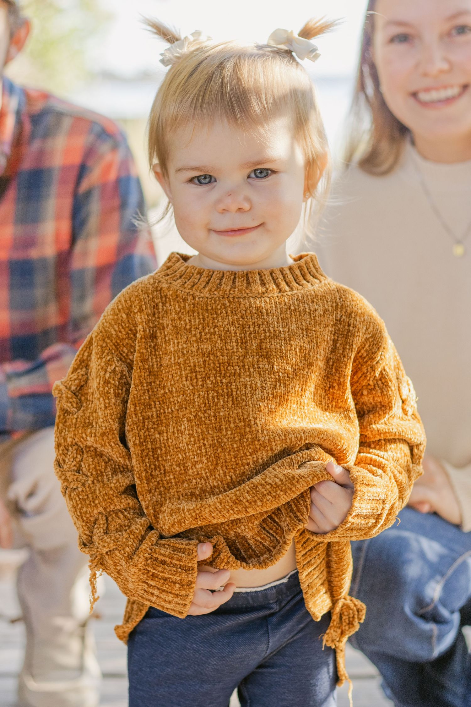 Young child wearing a cozy mustard yellow knit sweater poses with a bright smile.