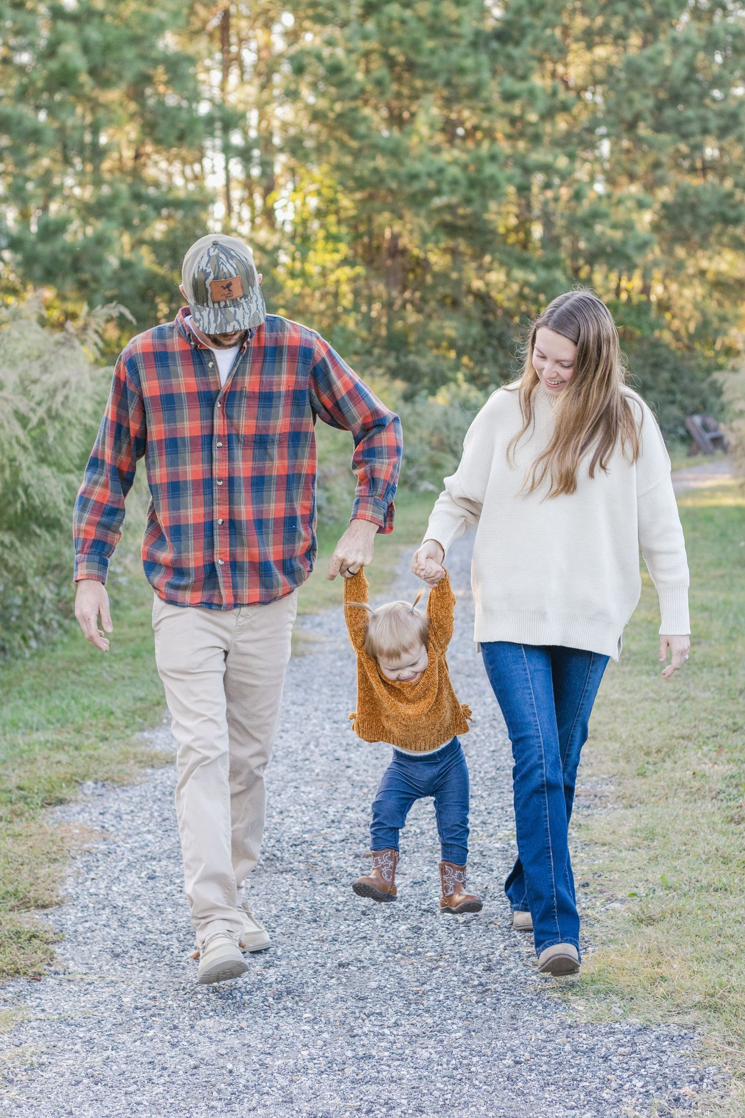 A family walks hand in hand down a gravel path while wearing coordinating plaid shirts and casual clothing.