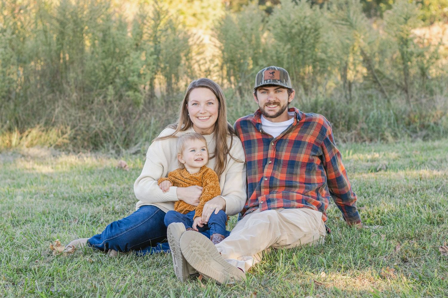 Family sitting together on grass during golden hour photo session.