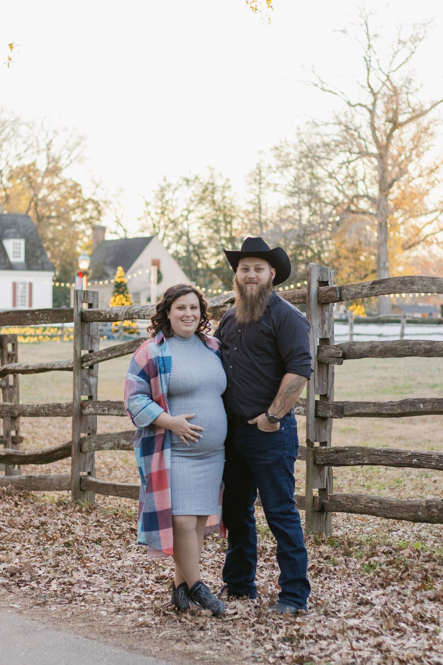 A couple shares a tender moment together by a rustic wooden fence surrounded by autumn leaves.