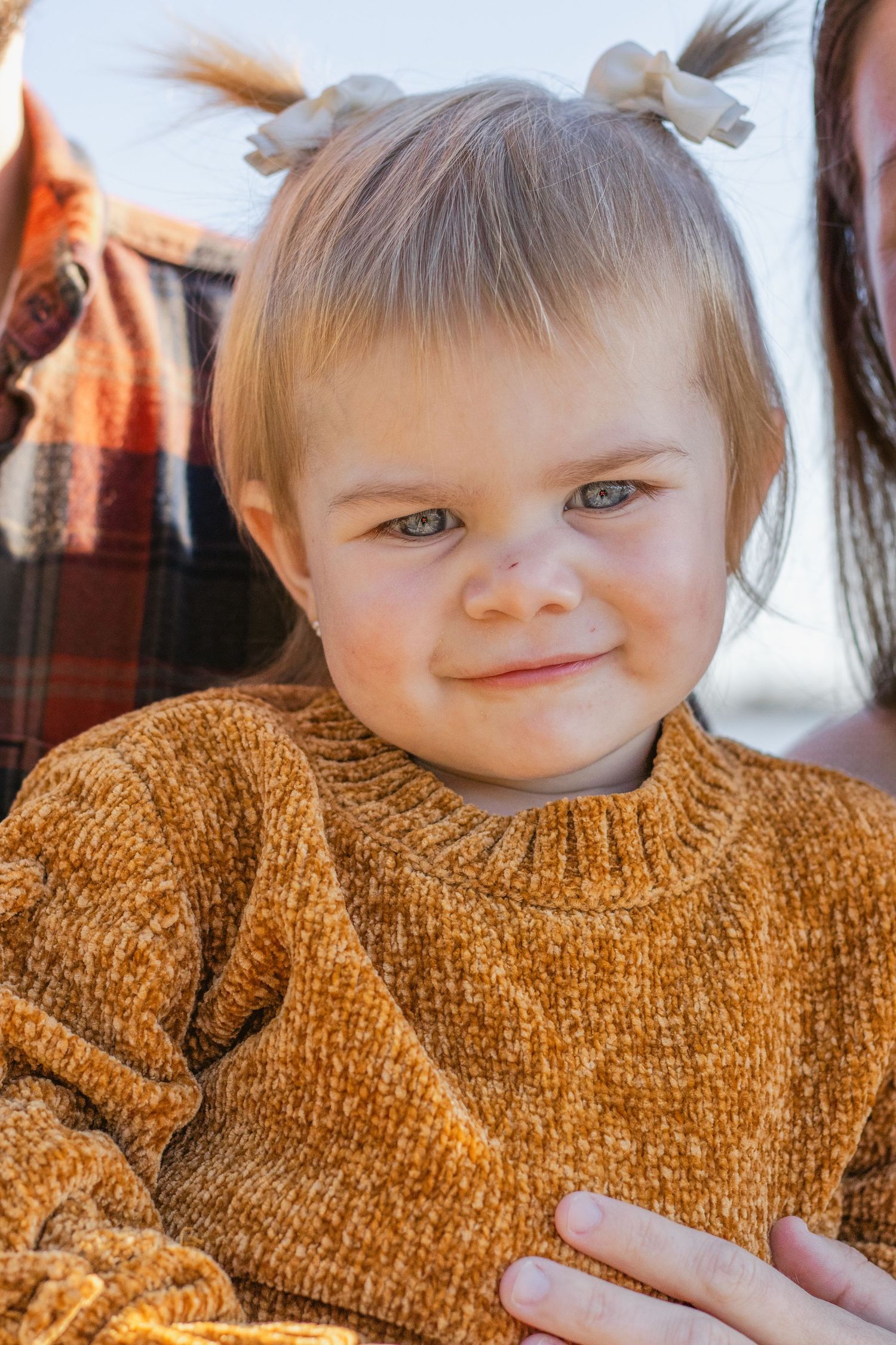 A sequence of four close-up photos showing someone with small pigtails wearing a cozy rust-colored sweater.