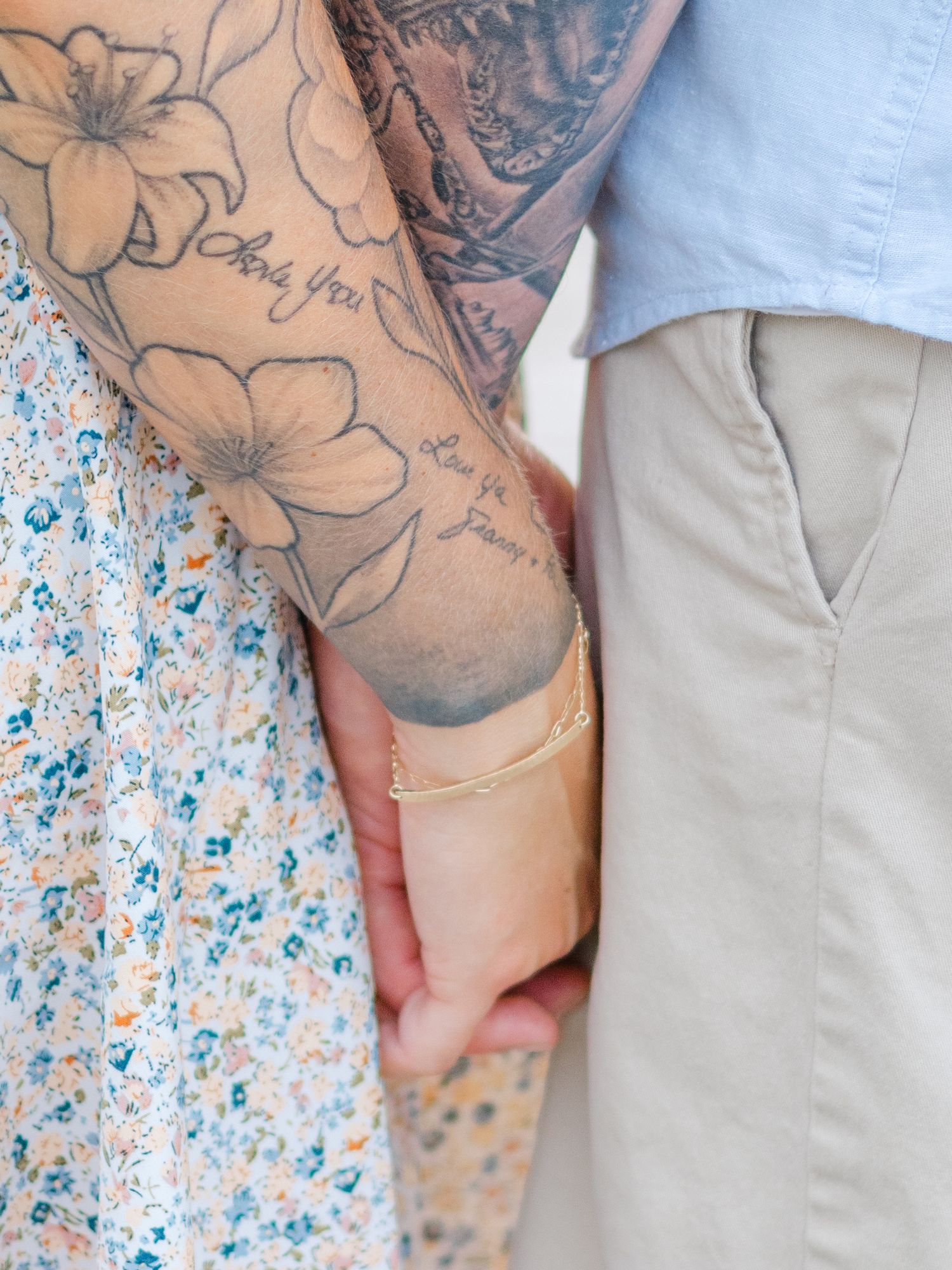 A person's arm showing floral tattoo artwork against a floral patterned background that coordinates with the design.