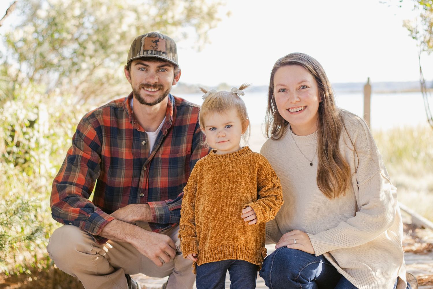 Casual family portrait session on wooden boardwalk near waterfront.