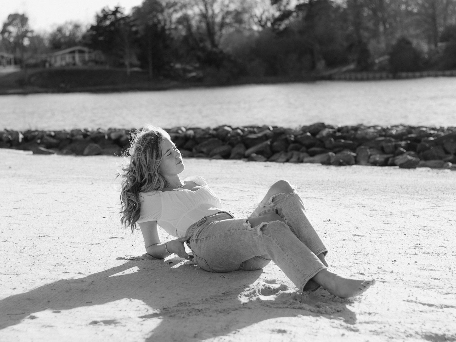 Eight monochromatic photographs showing a person lying on a sandy beach arranged in a horizontal sequence.