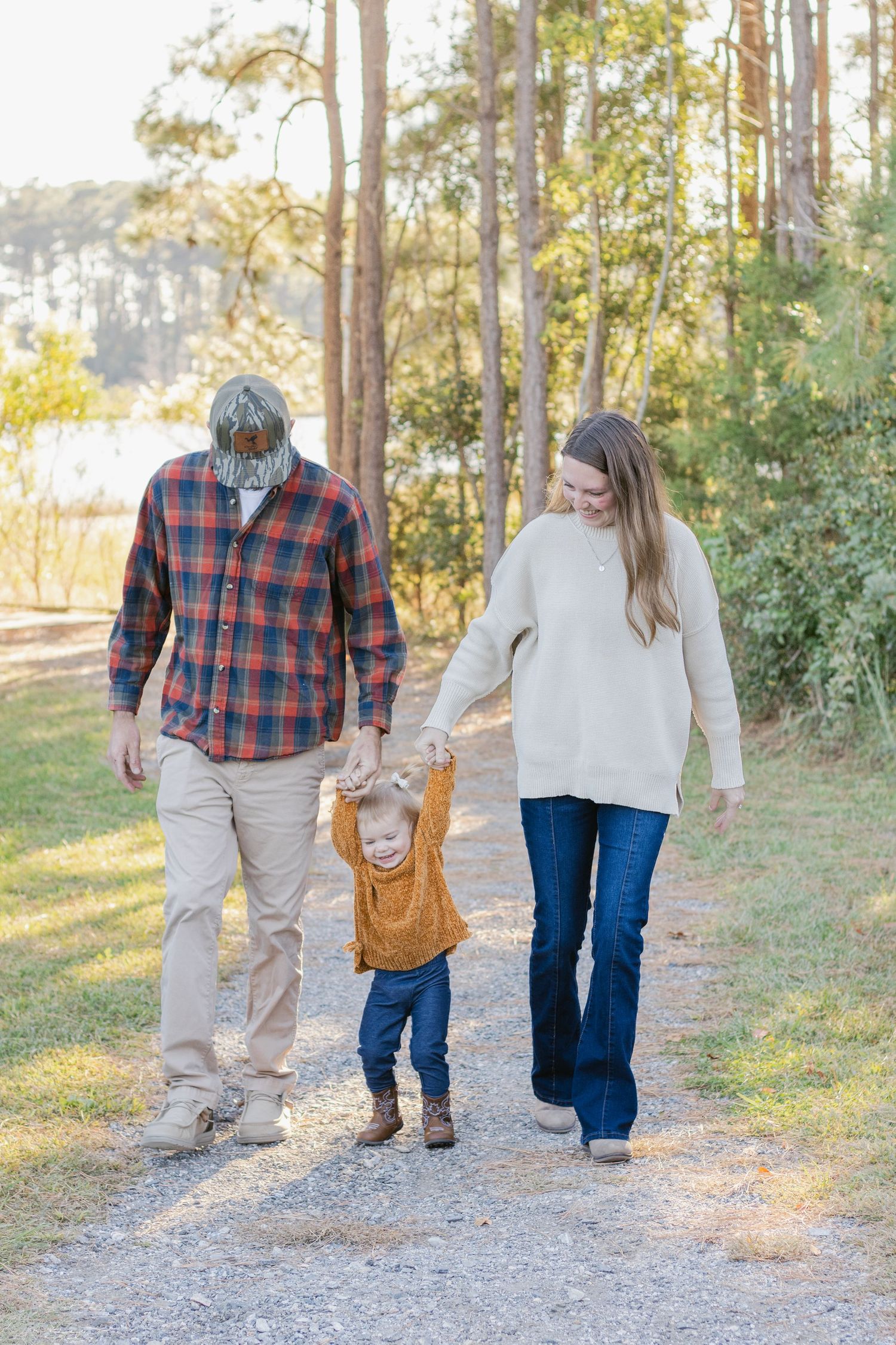 A family walks together on a nature trail during golden hour with tall pine trees in the background.