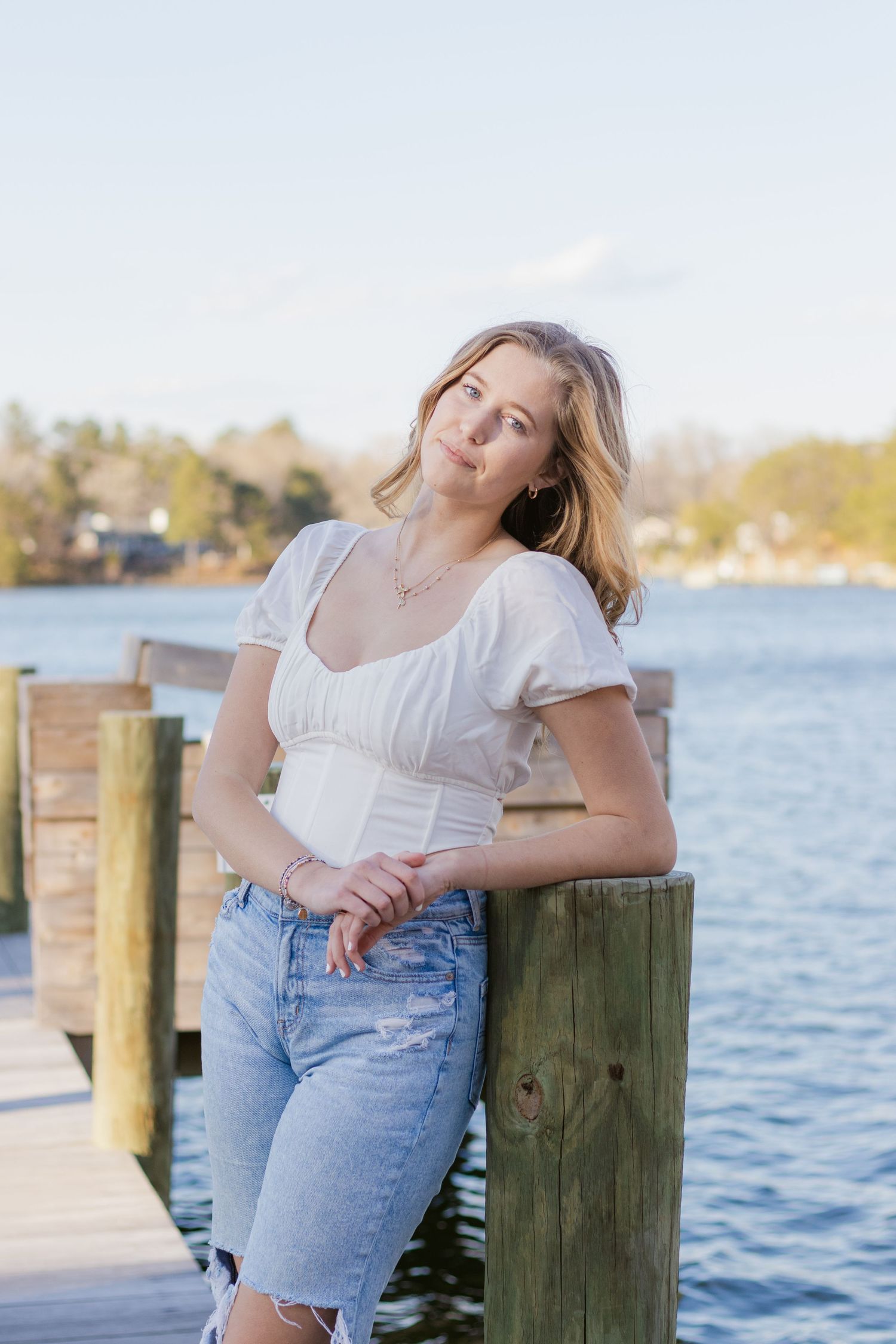 Three photos at a waterfront dock with denim and white outfits against wooden pilings and blue water backdrop.