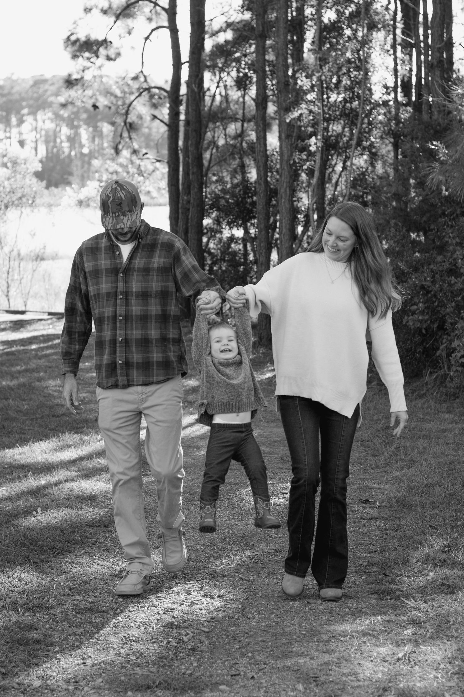 Family walking together on a wooded trail in black and white.