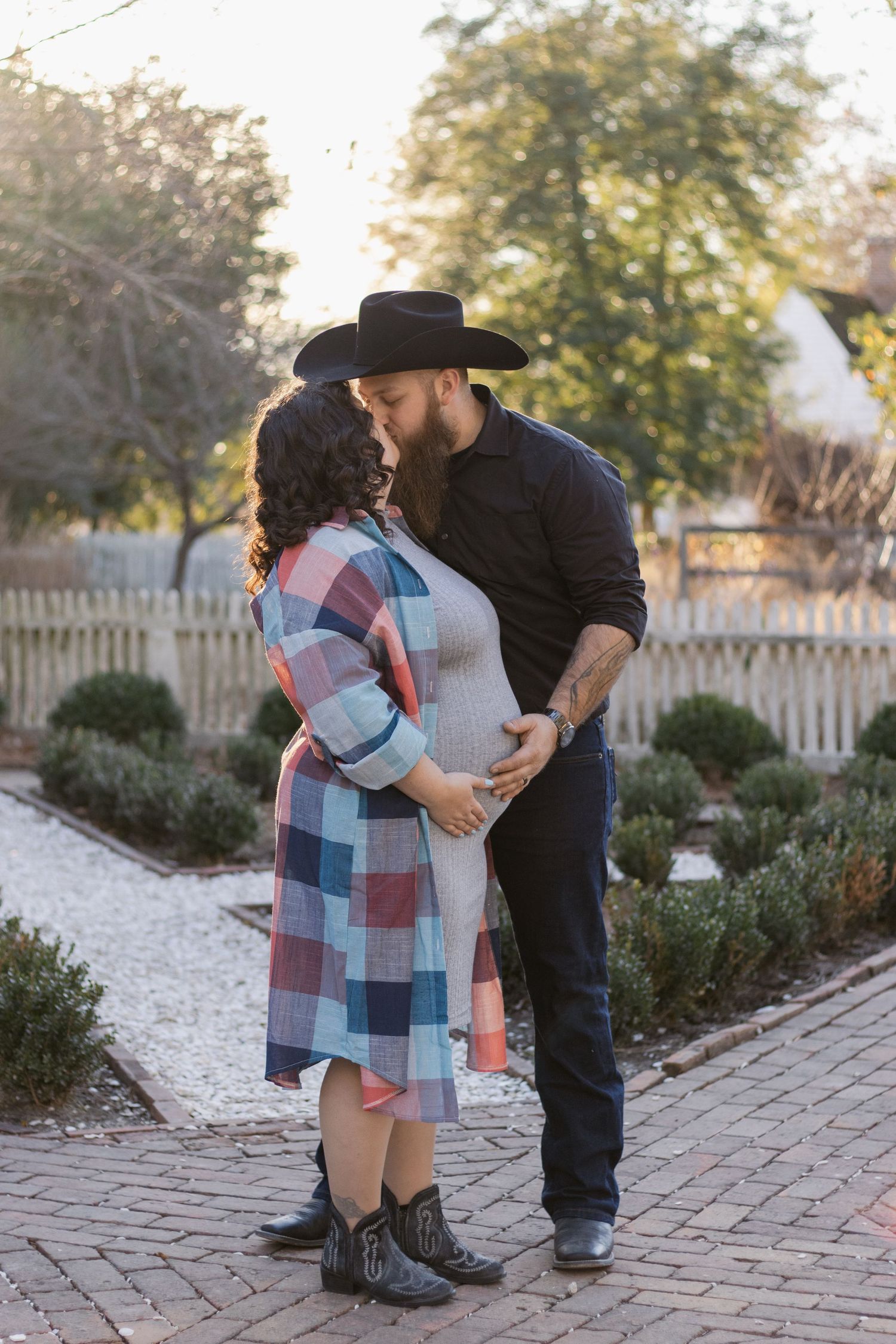 A couple in a garden path sharing a tender moment featuring plaid and western attire against an autumn background.