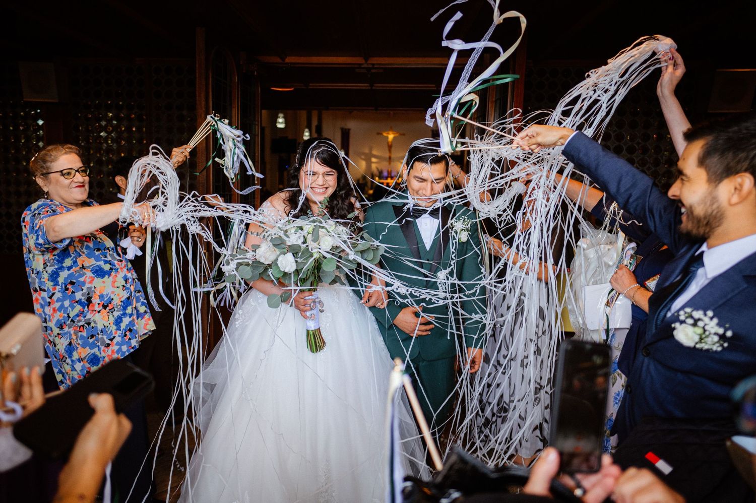 Wedding celebration with guests showering silver streamers over the happy couple.