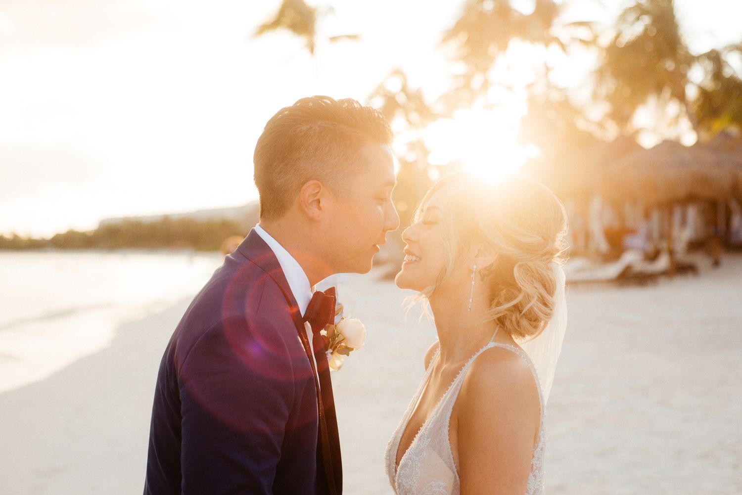 Newlyweds share a tender moment on a tropical beach at golden hour.