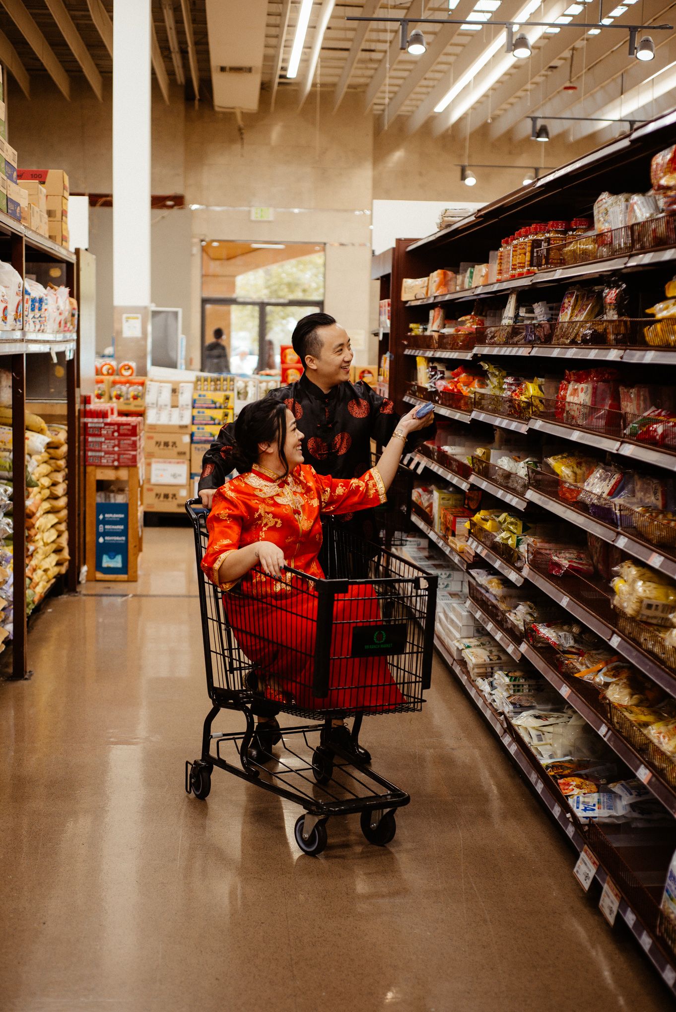 Shopping together in traditional red attire at a grocery store snack aisle.