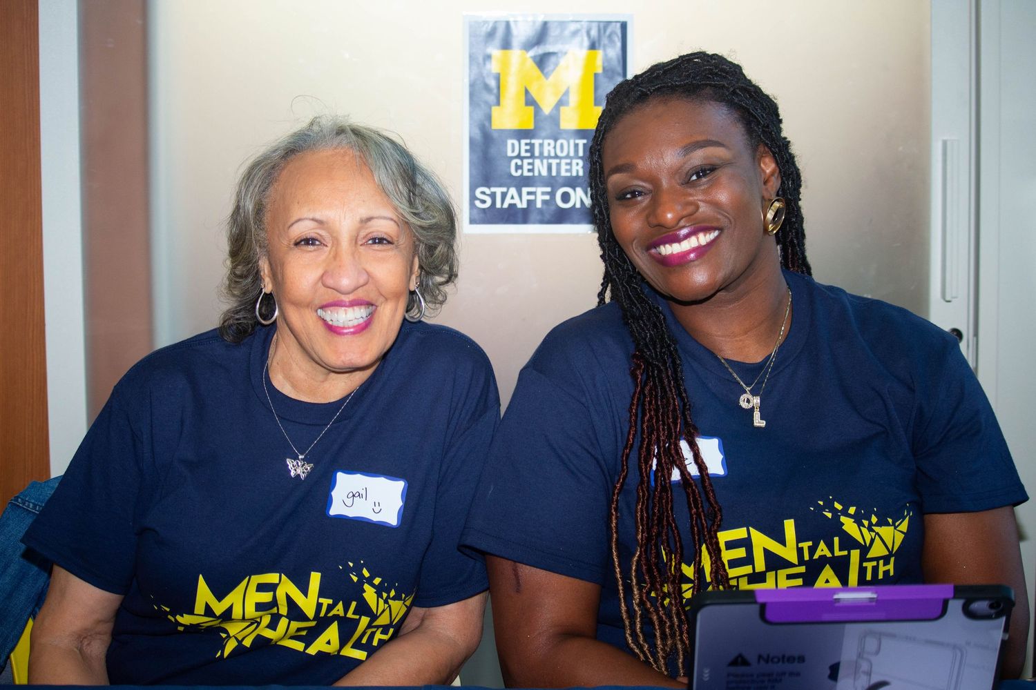 Two women smiling in matching Mental Health awareness t-shirts at a Detroit Center staff event.