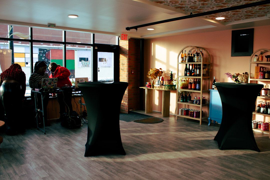 Modern cafe interior with black cocktail tables, wood floors, and a retail display shelf.