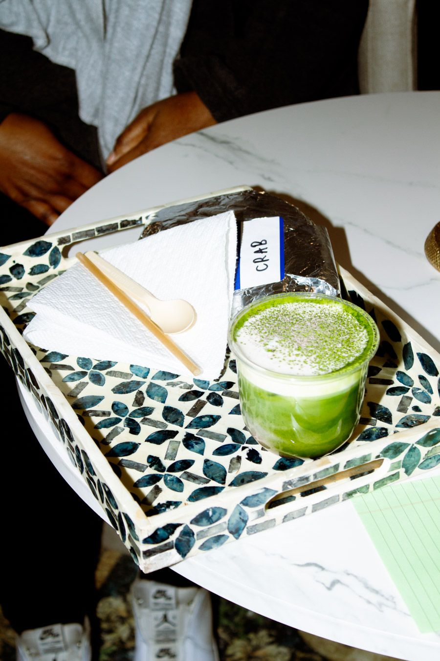 Vibrant green matcha latte served on a decorative tray with a wooden spoon.
