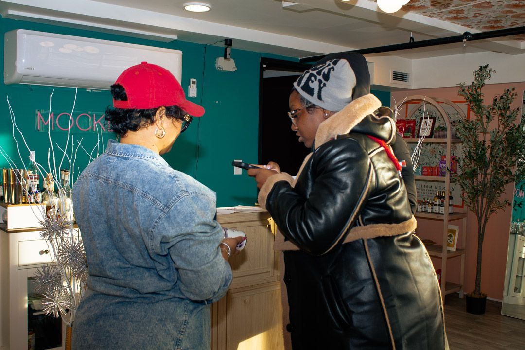 Two people looking at a phone inside a colorful cafe with teal walls.