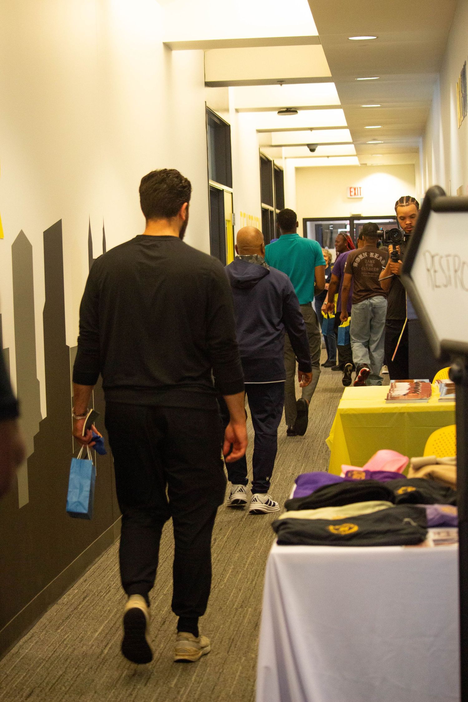 Attendees walking through hallway vendor area at Mental Health Detroit conference with merchandise tables.