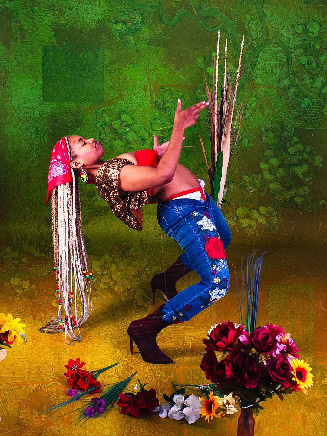 Woman in colorful outfit with long braids poses dramatically among flowers against a green background.